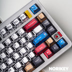 Close-up of colorful comic style modifier keycaps with red blue and yellow dye-sub legends on Cherry profile PBT